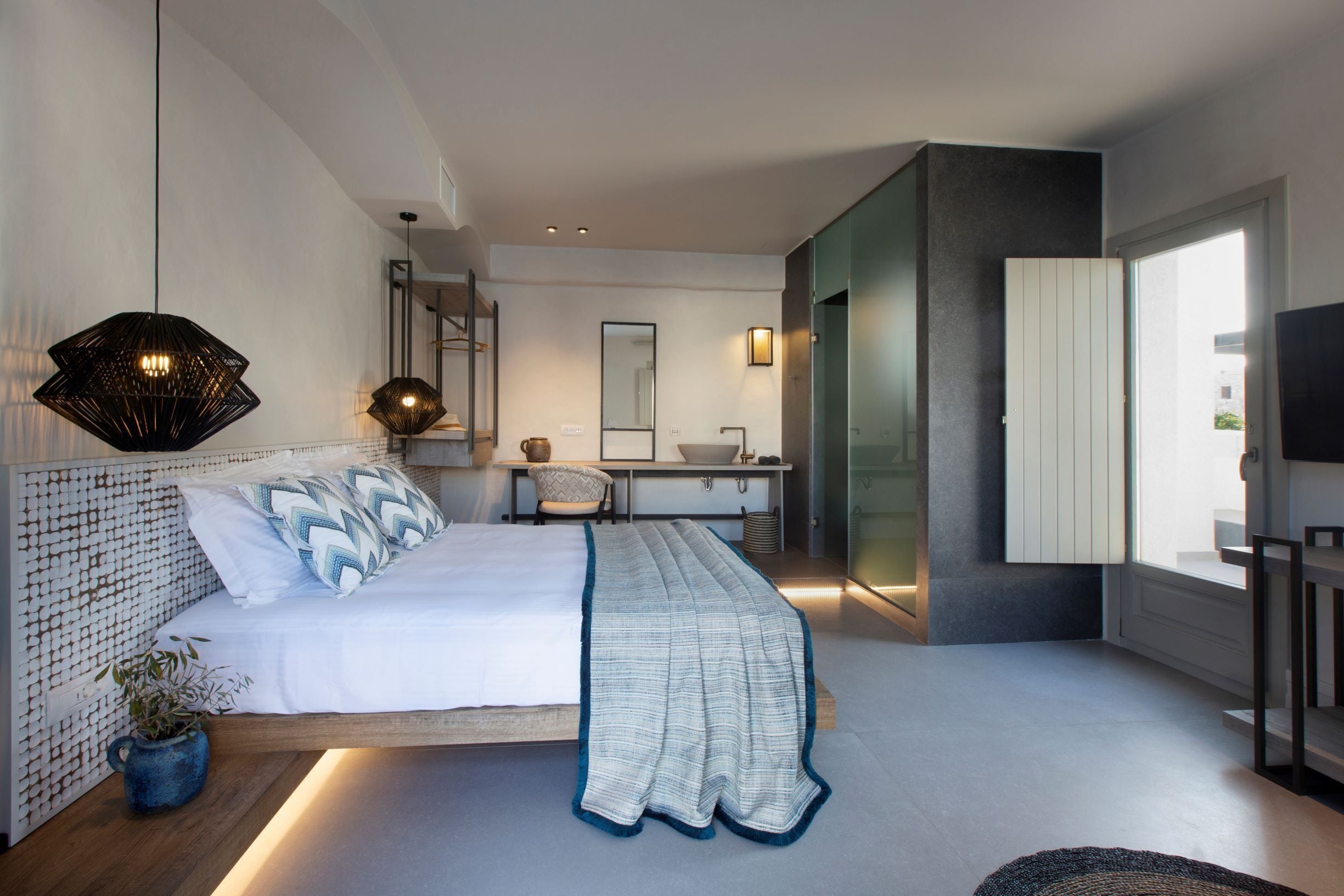A modern bedroom with a bed, bedside table, and a large mirror.