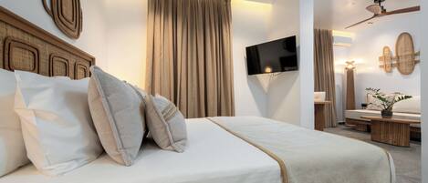 Une chambre moderne avec un grand lit, un ventilateur de plafond, un téléviseur à écran plat et un téléviseur fixé au mur.