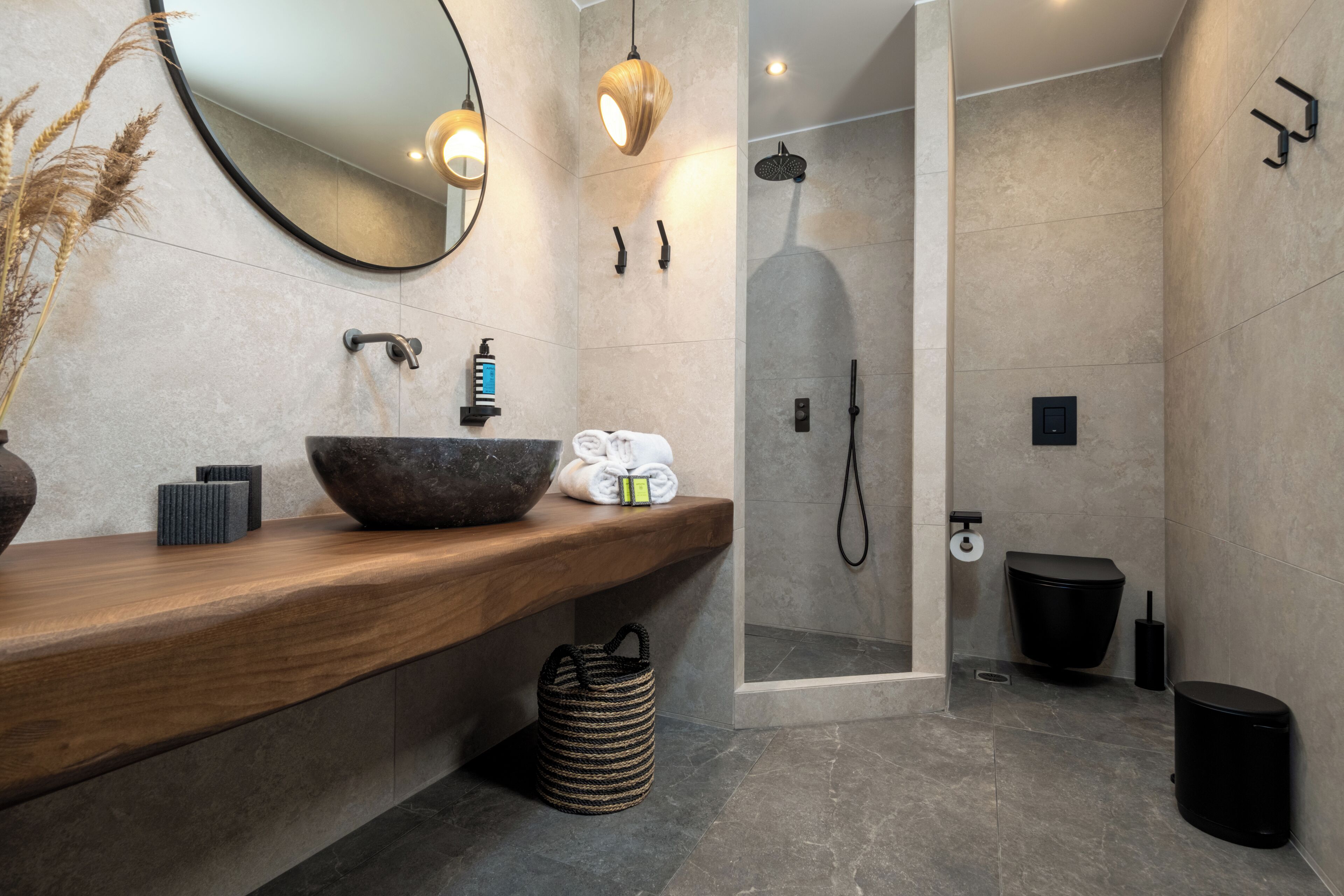 Un baño moderno con tocador de madera, un espejo grande y zona de ducha.