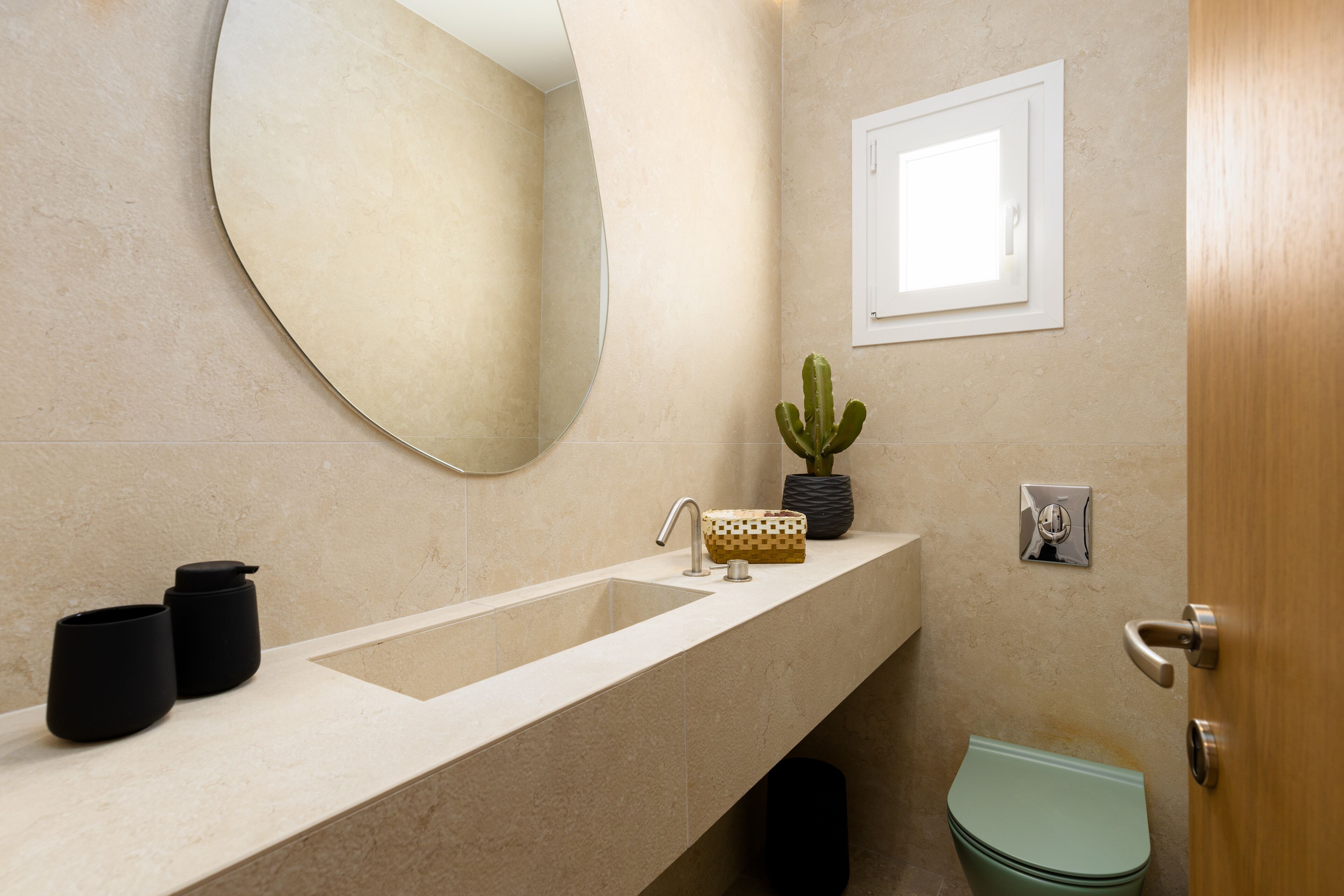Un baño con un espejo grande, un lavabo, un inodoro y una puerta.