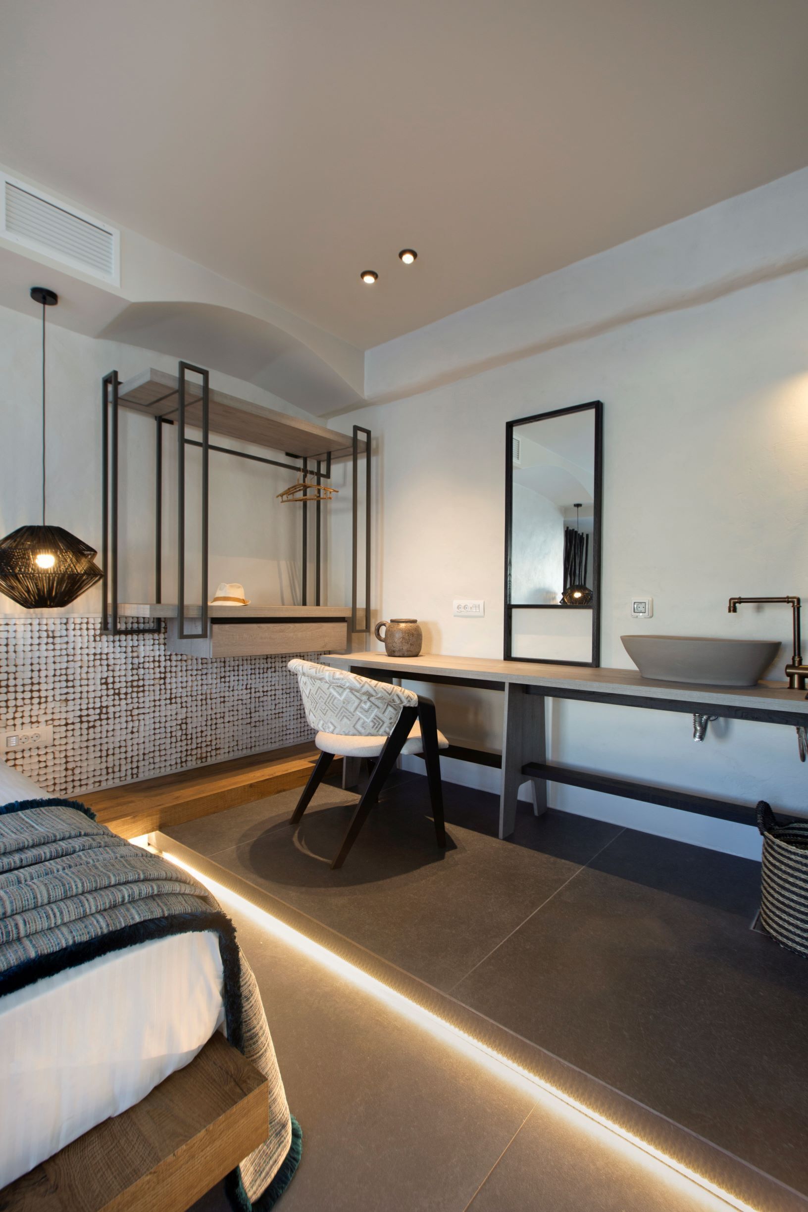 A modern bedroom with a bed, bedside table, chair, and a large mirror.