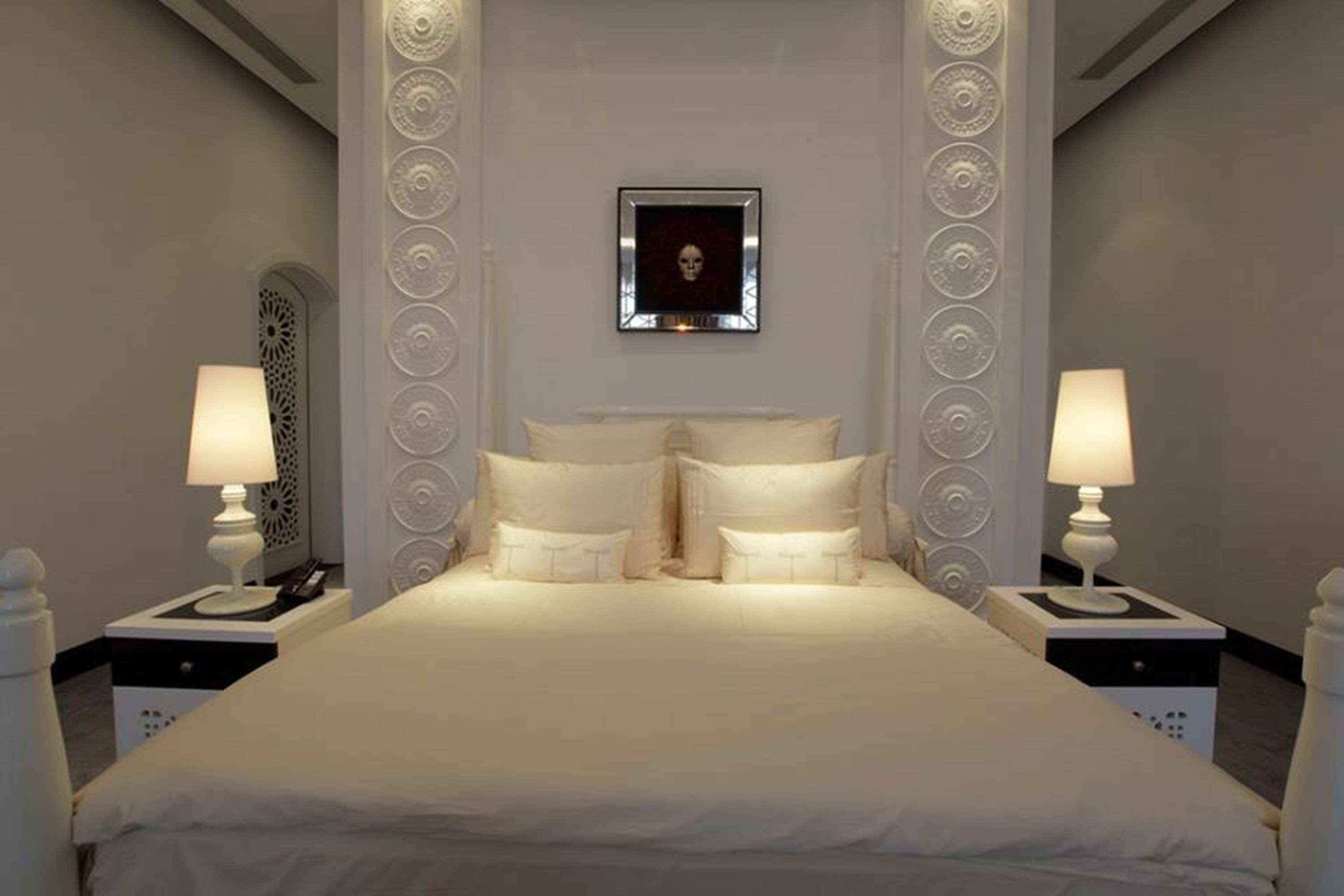 A neatly arranged hotel room with a large bed, two bedside tables with lamps, and a framed artwork on the wall.