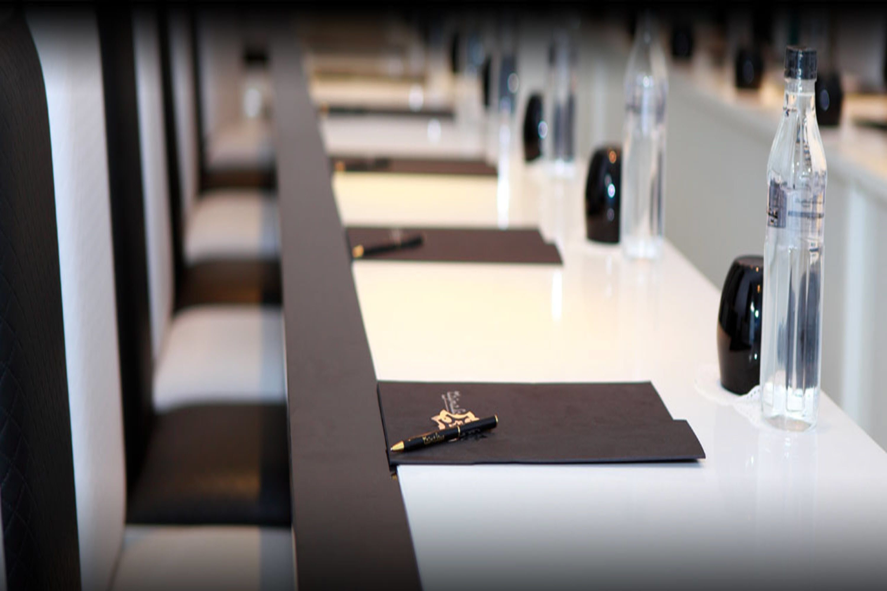 A conference room with a long table, black chairs, and water bottles.