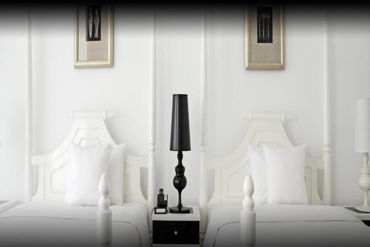 A hotel room with two beds, white bedding, a black lamp on each nightstand, and framed artwork on the walls.