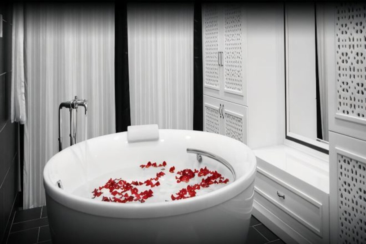 A modern bathroom with a freestanding bathtub, a window, and a shower area.
