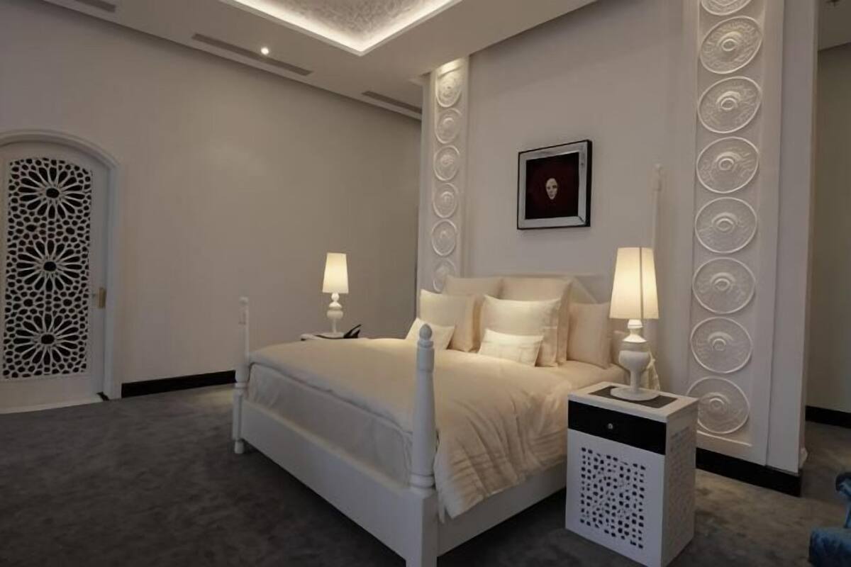A bedroom with a bed, bedside lamps, a nightstand, and decorative wall panels.