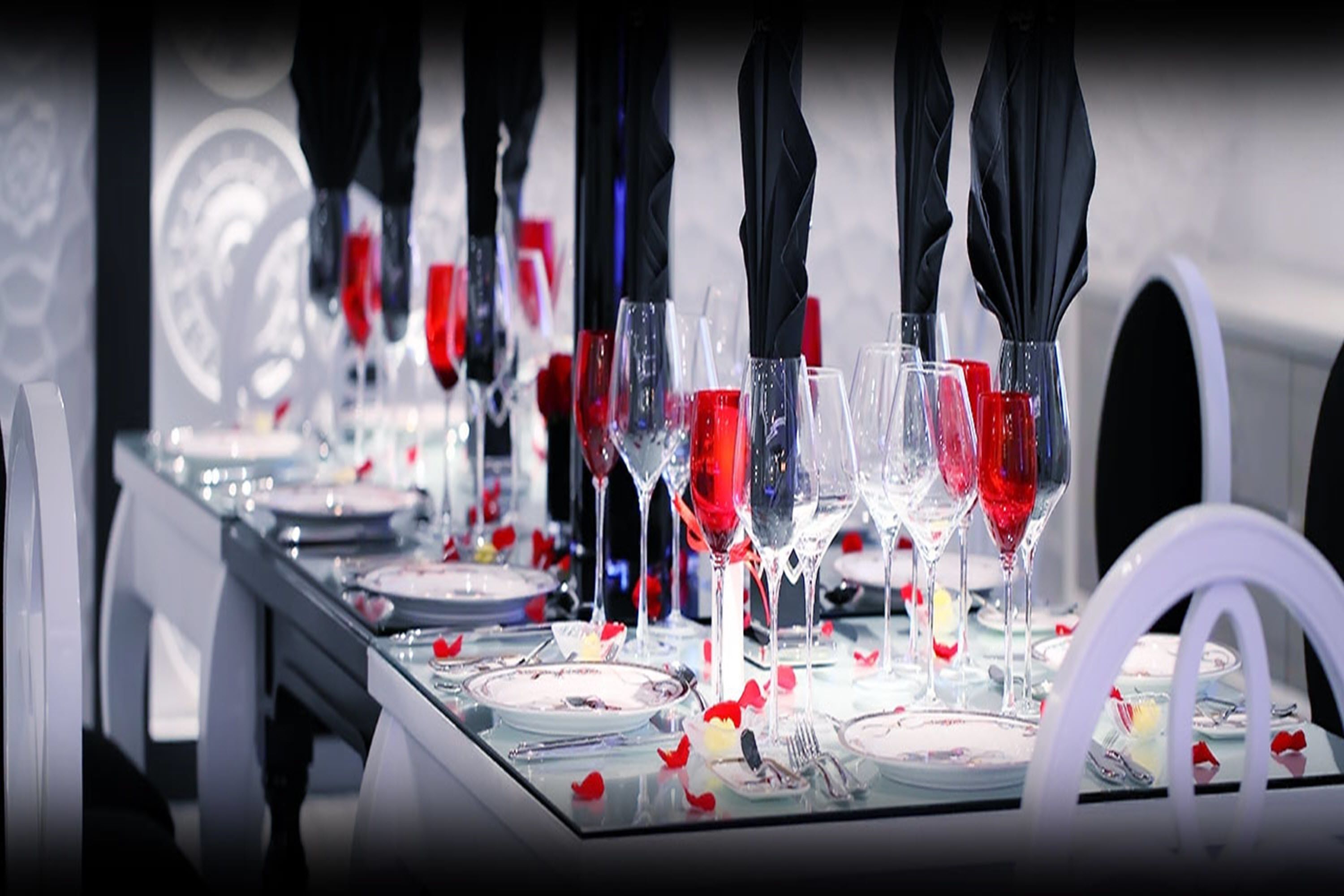 A table set with wine glasses, plates, and cutlery, with black umbrellas above.