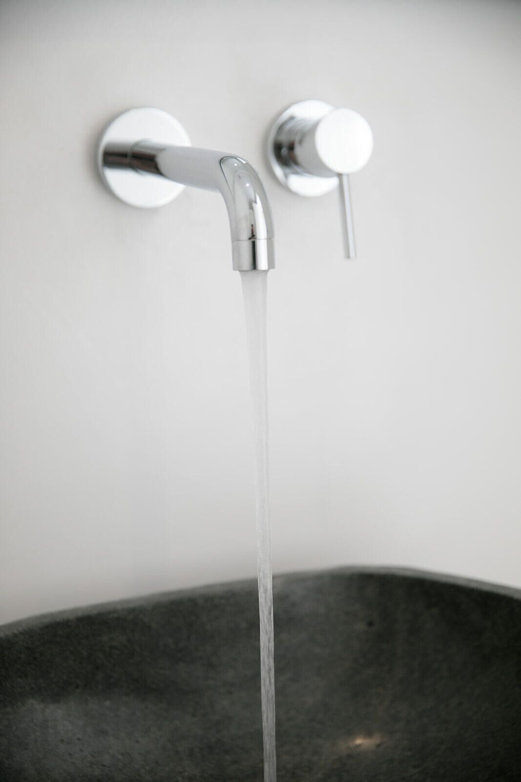 A modern bathroom with a single chrome faucet and a black sink.