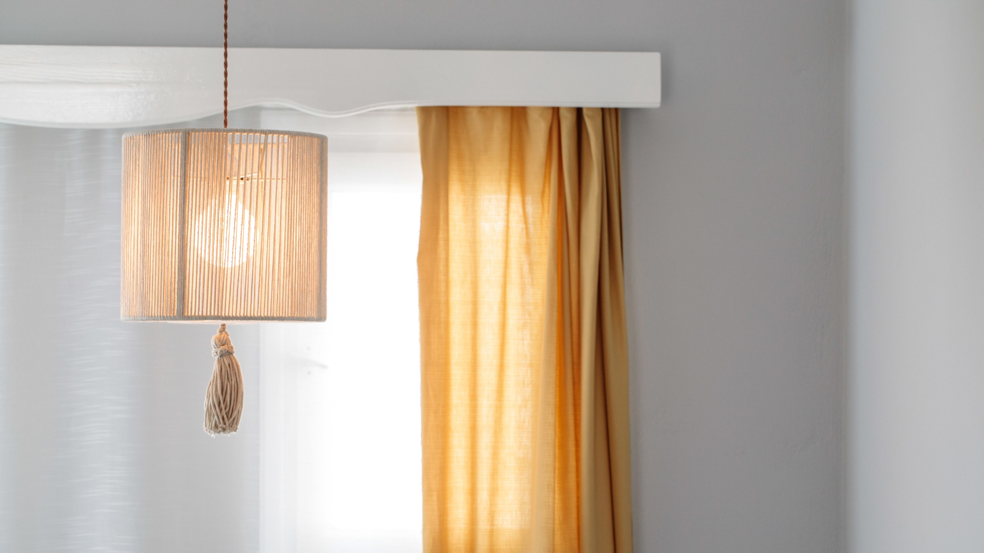 A room with a hanging lamp, a curtain, and a white ceiling.