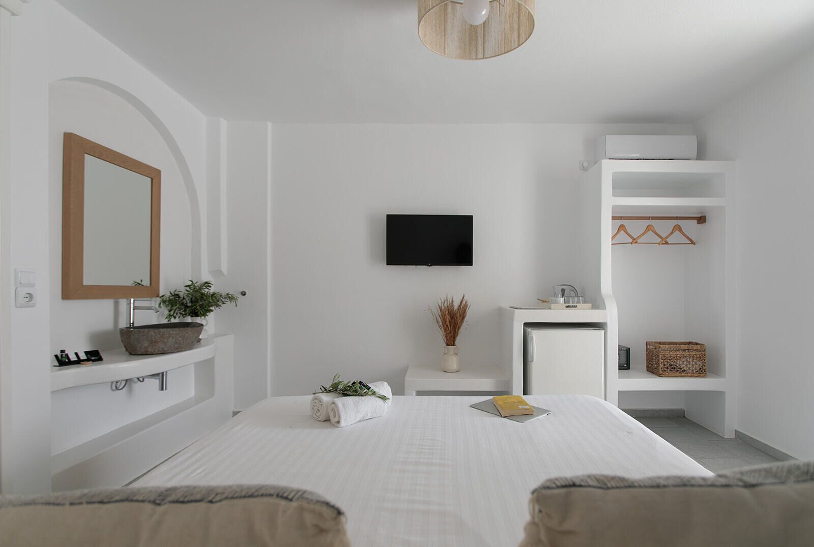 Un dormitorio moderno con cama, televisor, escritorio pequeño y armario.