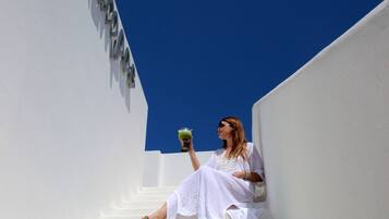 Une personne assise sur des marches blanches, avec un ciel bleu clair en arrière-plan.