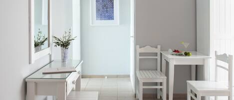 Quarto moderno e minimalista com móveis brancos, uma mesa de vidro e uma obra de arte emoldurada na parede.