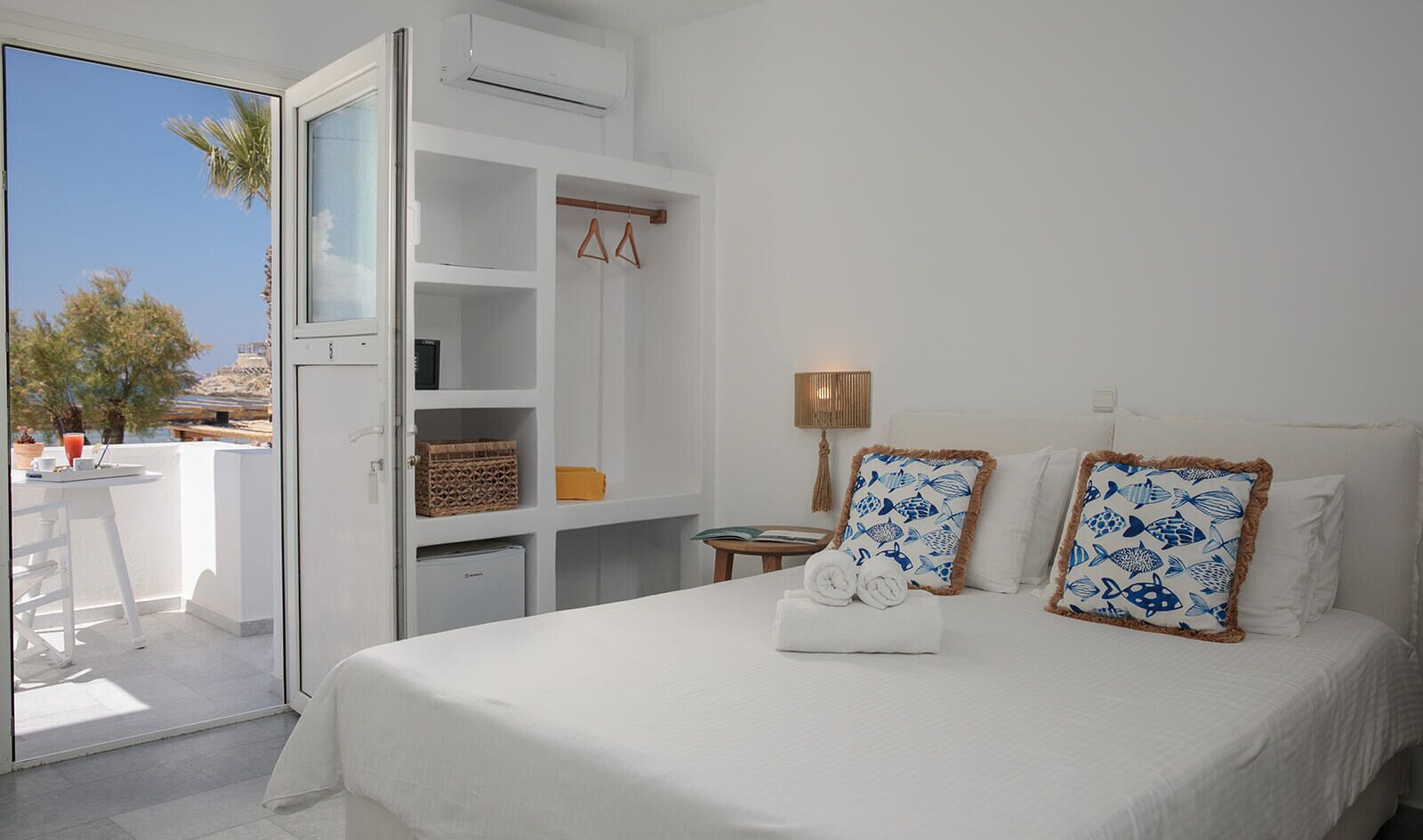 Une chambre d’hôtel avec un lit, une armoire, une petite table avec une lampe et une vue sur l’extérieur.
