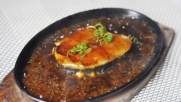 A dish with a dark sauce and green garnish on a black plate.