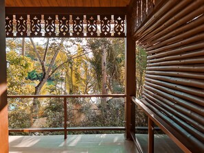 Ein Zimmer mit einem großen Fenster mit Blick auf einen Garten, Bäume und einen Teich.
