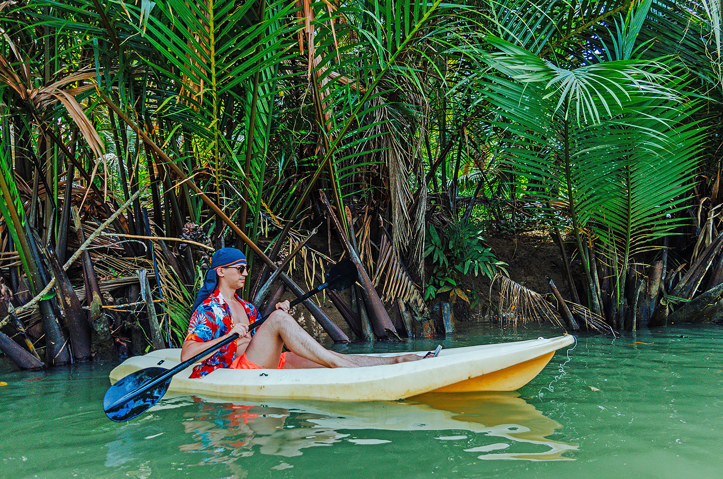 A person in a kayak in a water body surrounded by dense vegetation.