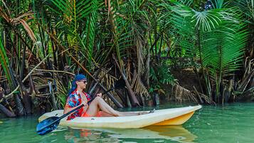 A person in a kayak in a water body surrounded by dense vegetation.