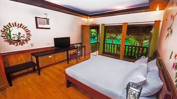 Une chambre à coucher avec un lit, un bureau, une télévision et une vue sur la verdure.