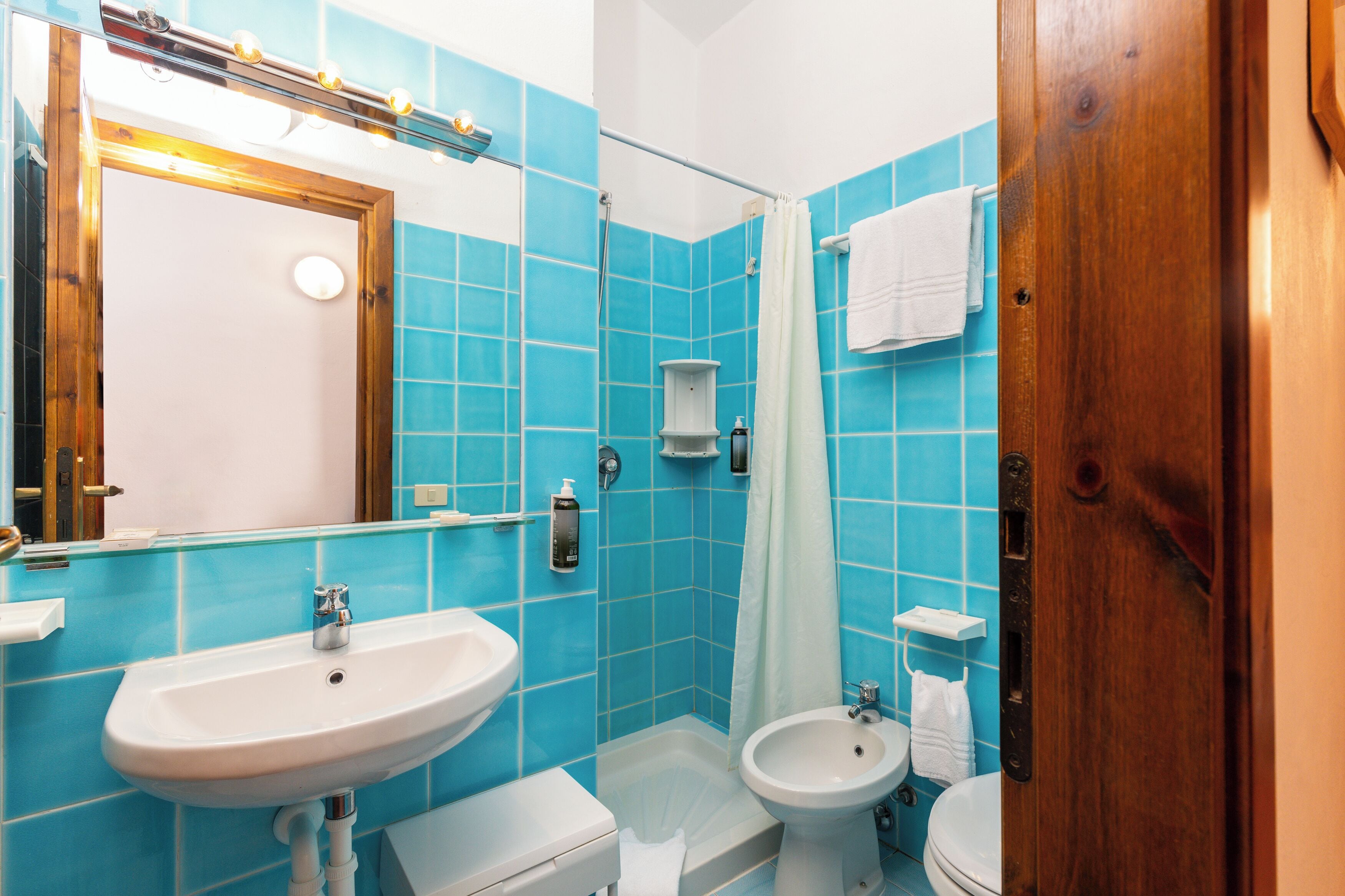 A bathroom with a sink, bidet, and toilet, all with white fixtures.