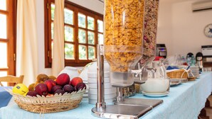 A breakfast buffet setup with cereal dispensers, a fruit basket, and a milk jug. - Piccolo Pevero (Arzachena)