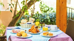 A breakfast table with croissants, pastries, fruit, and juice. - Piccolo Pevero (Arzachena)