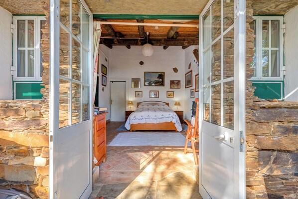 A bedroom with a bed, wooden dresser, and stone walls.