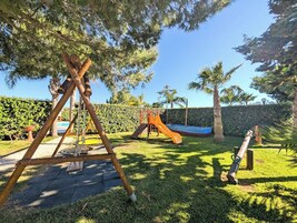 Un'area giochi con altalene, scivolo e struttura per arrampicata.
