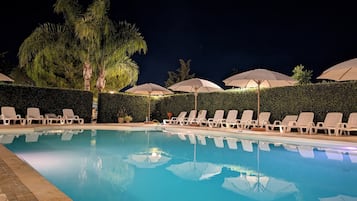 Una piscina al aire libre, sombrillas, tumbonas