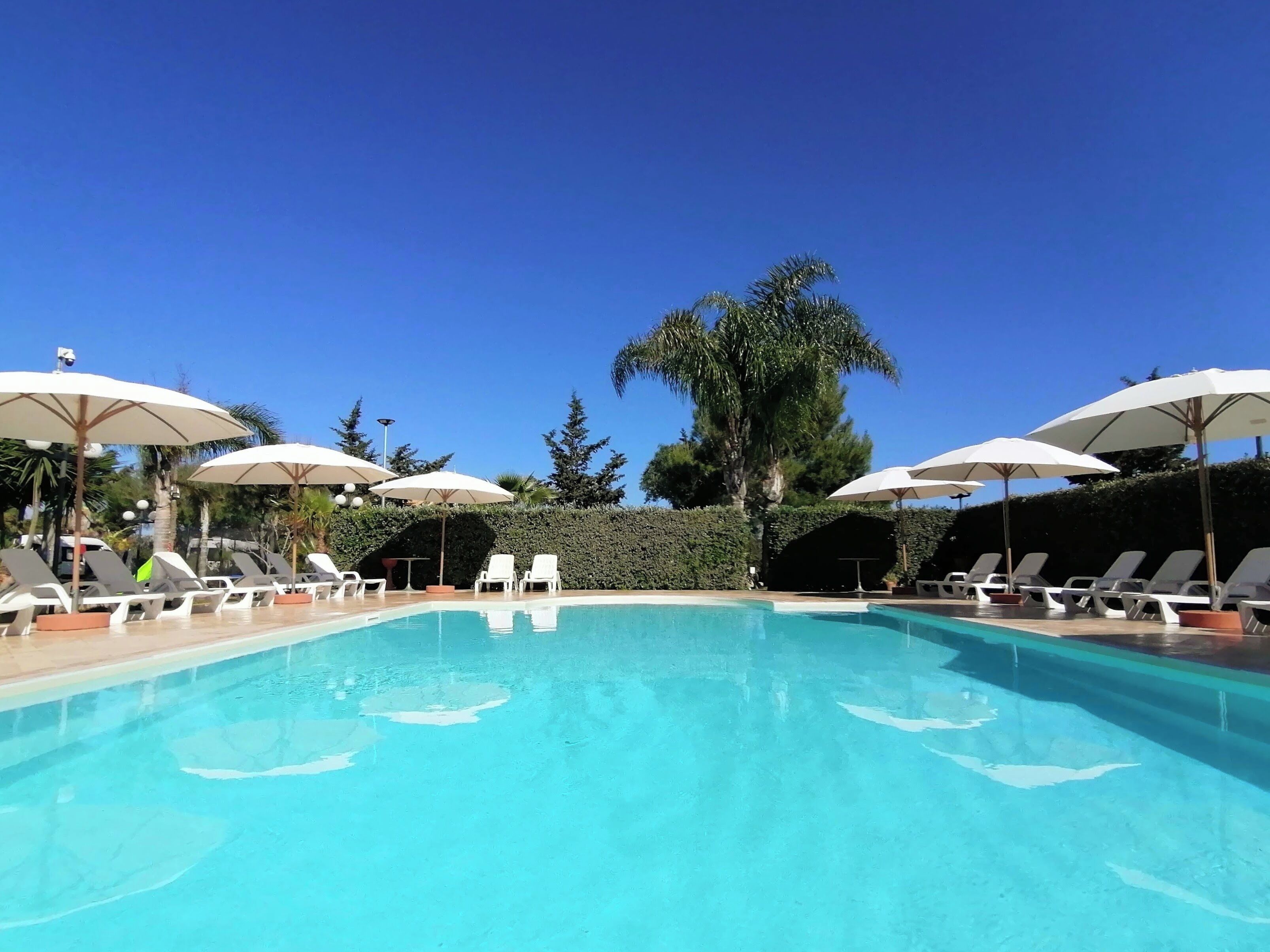 Una piscina al aire libre de temporada, sombrillas, tumbonas