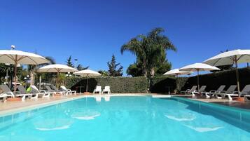 Una piscina al aire libre de temporada, sombrillas, tumbonas