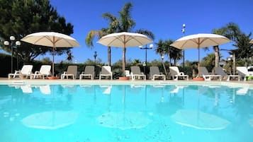 Una piscina al aire libre de temporada, sombrillas
