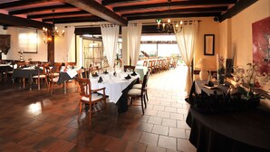 A restaurant with wooden tables and chairs, a chandelier, and a view of the outdoors. - Sud Hôtel (Huttenheim)