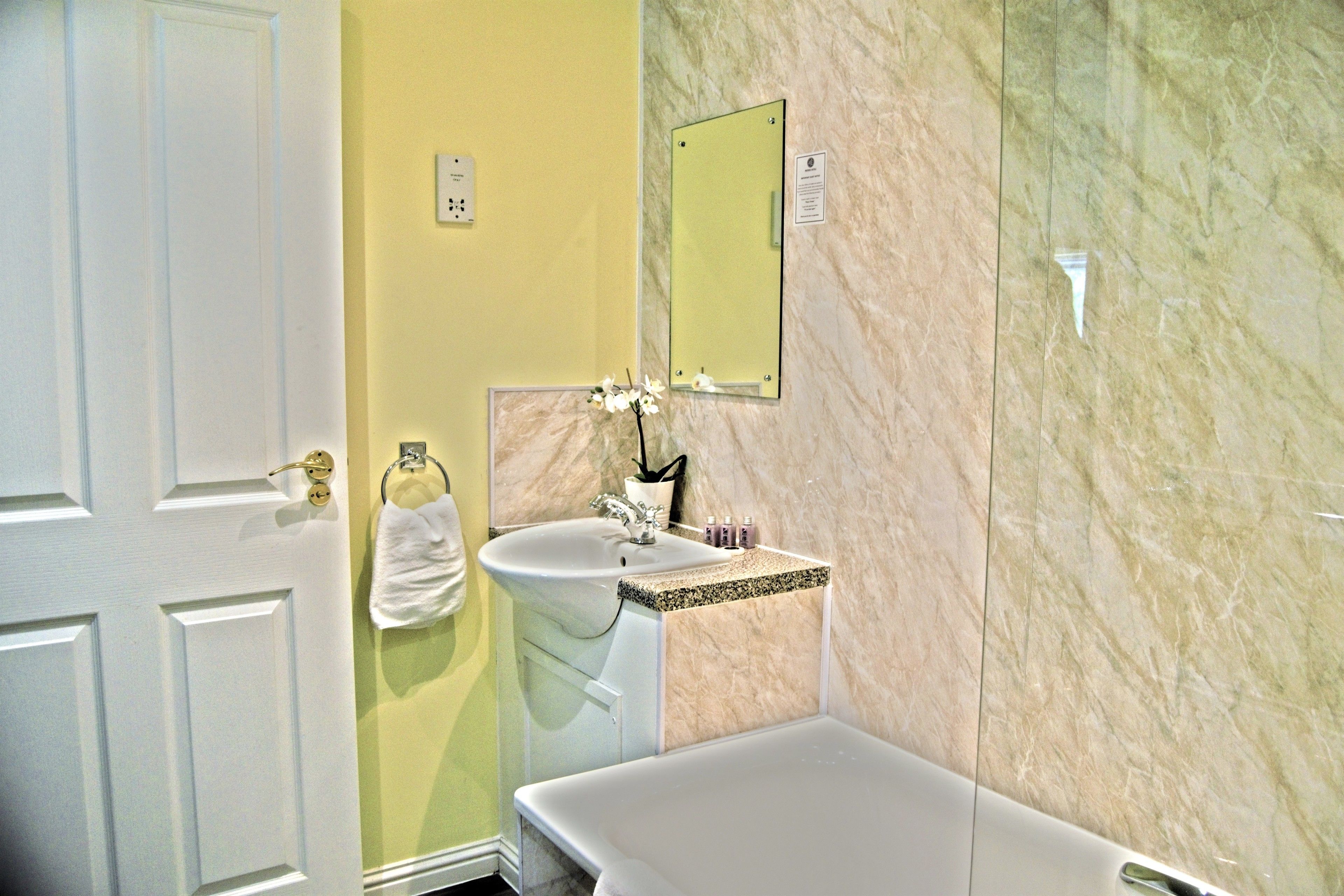 A bathroom with a white bathtub, a sink with a marble countertop, and a mirror on the wall.
