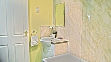 A bathroom with a white bathtub, a sink with a marble countertop, and a mirror on the wall.
