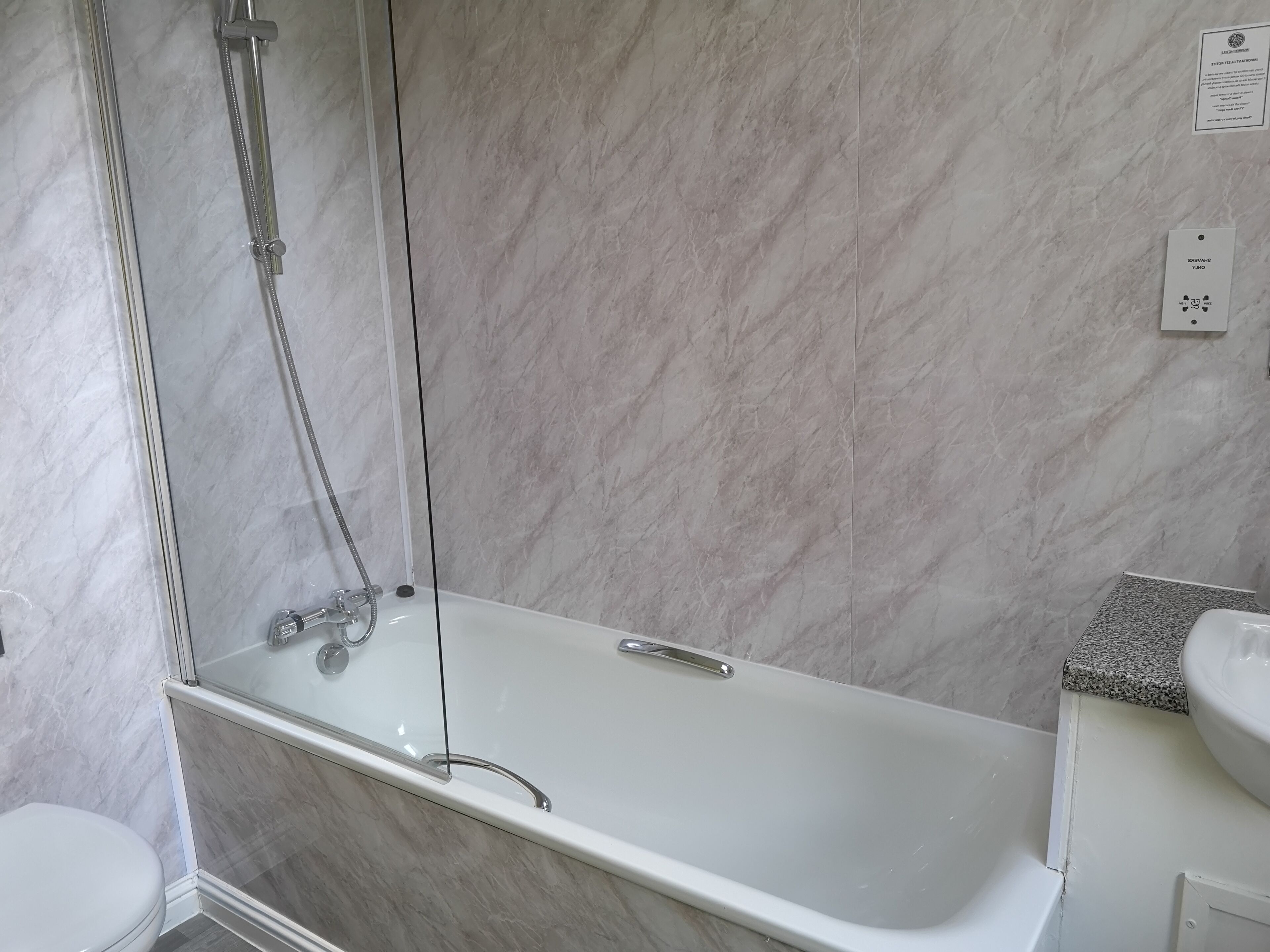 Een moderne badkamer met een douchecabine van glas, een witte badkuip en een wastafel met een granieten blad.