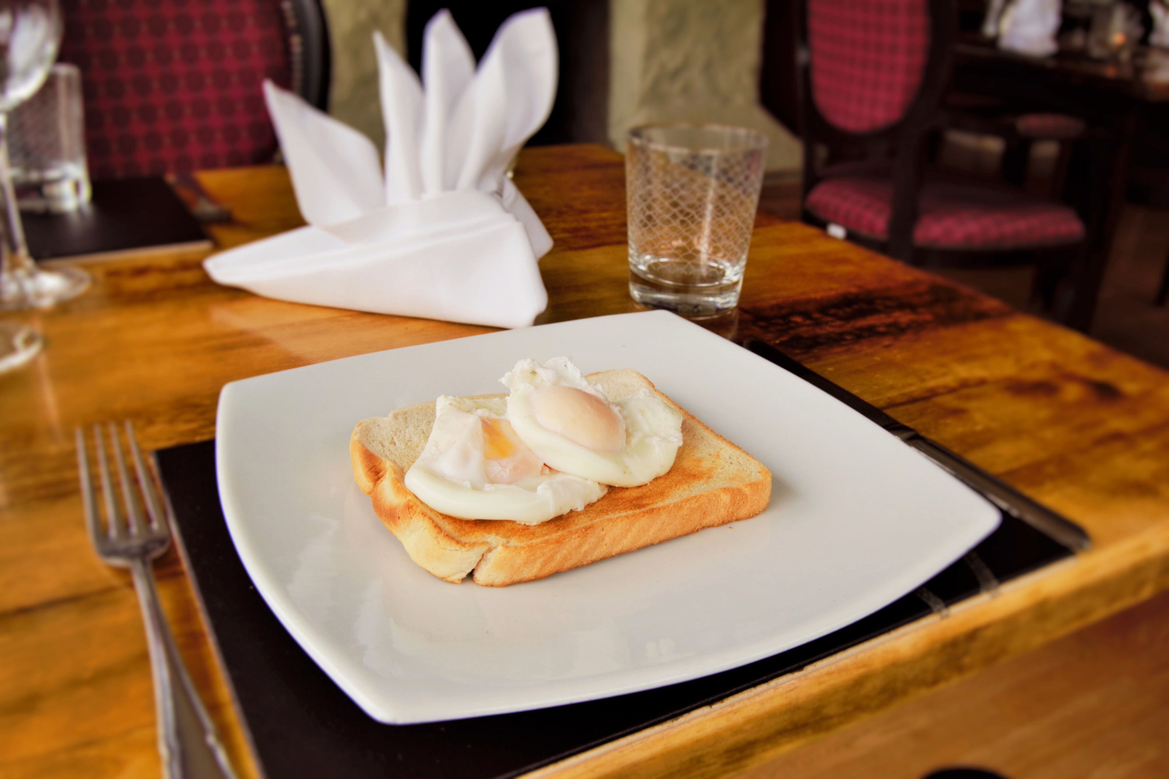 A breakfast plate with toast and a poached egg on a white plate.