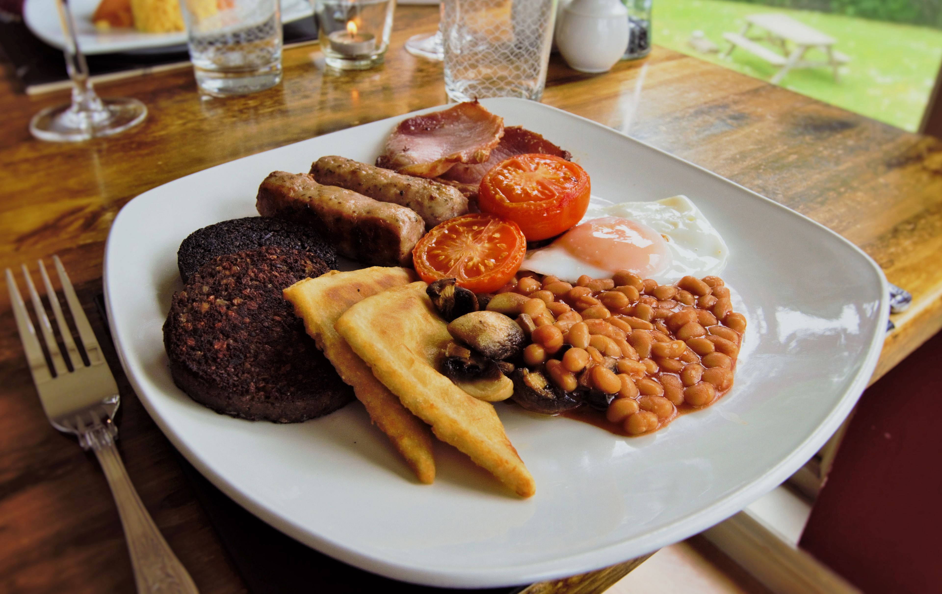 Un plato de comida para el desayuno con salchichas, huevos, tomates, frijoles y tostadas.