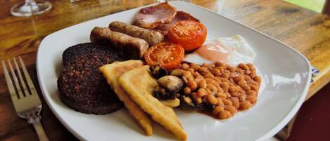Un plato de comida para el desayuno con salchichas, huevos, tomates, frijoles y tostadas.