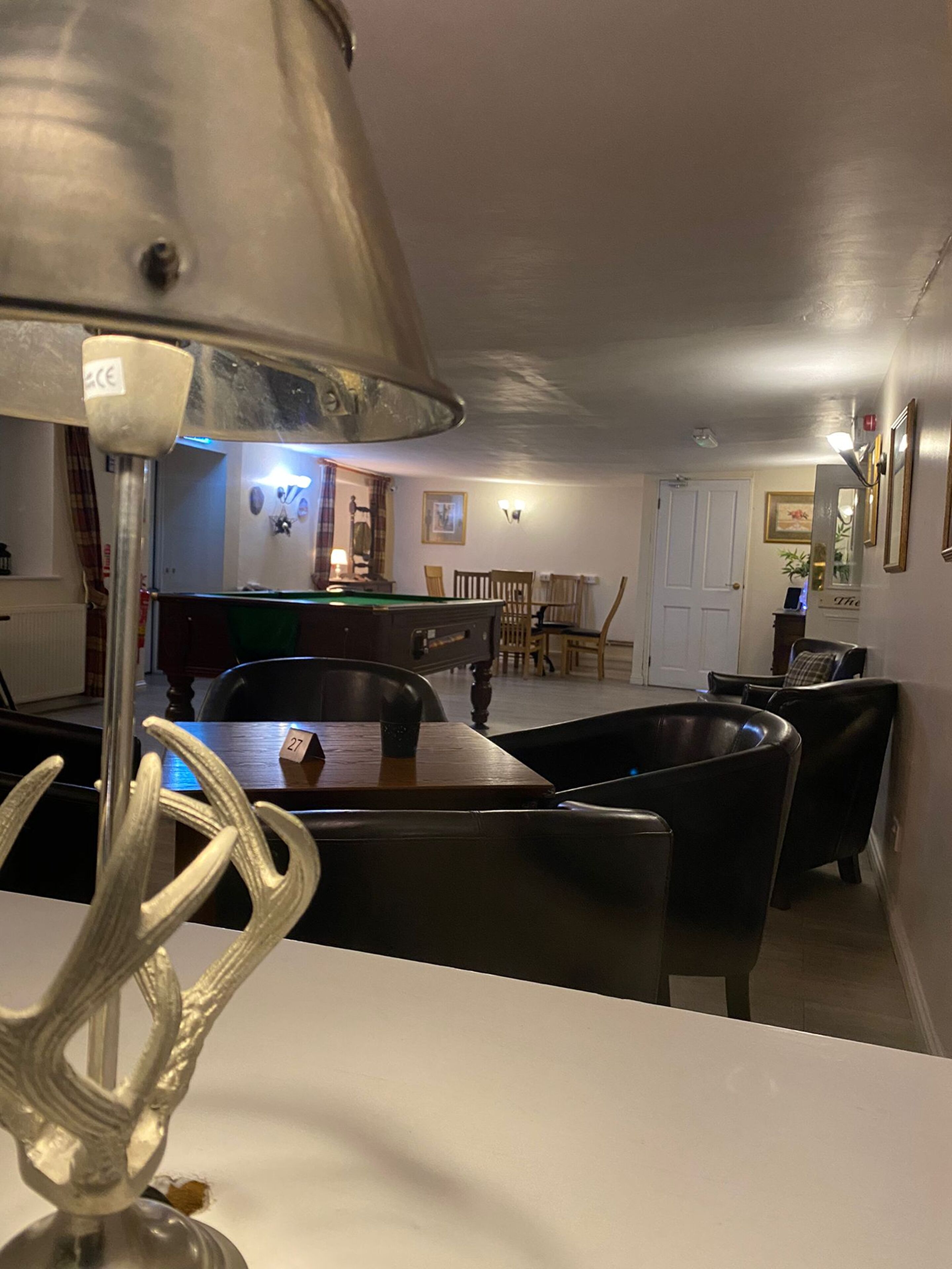A room with a pool table, chairs, a lamp, and a dining table.