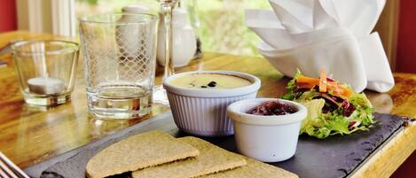 A meal with bread, a salad, and two small bowls of soup on a slate plate.