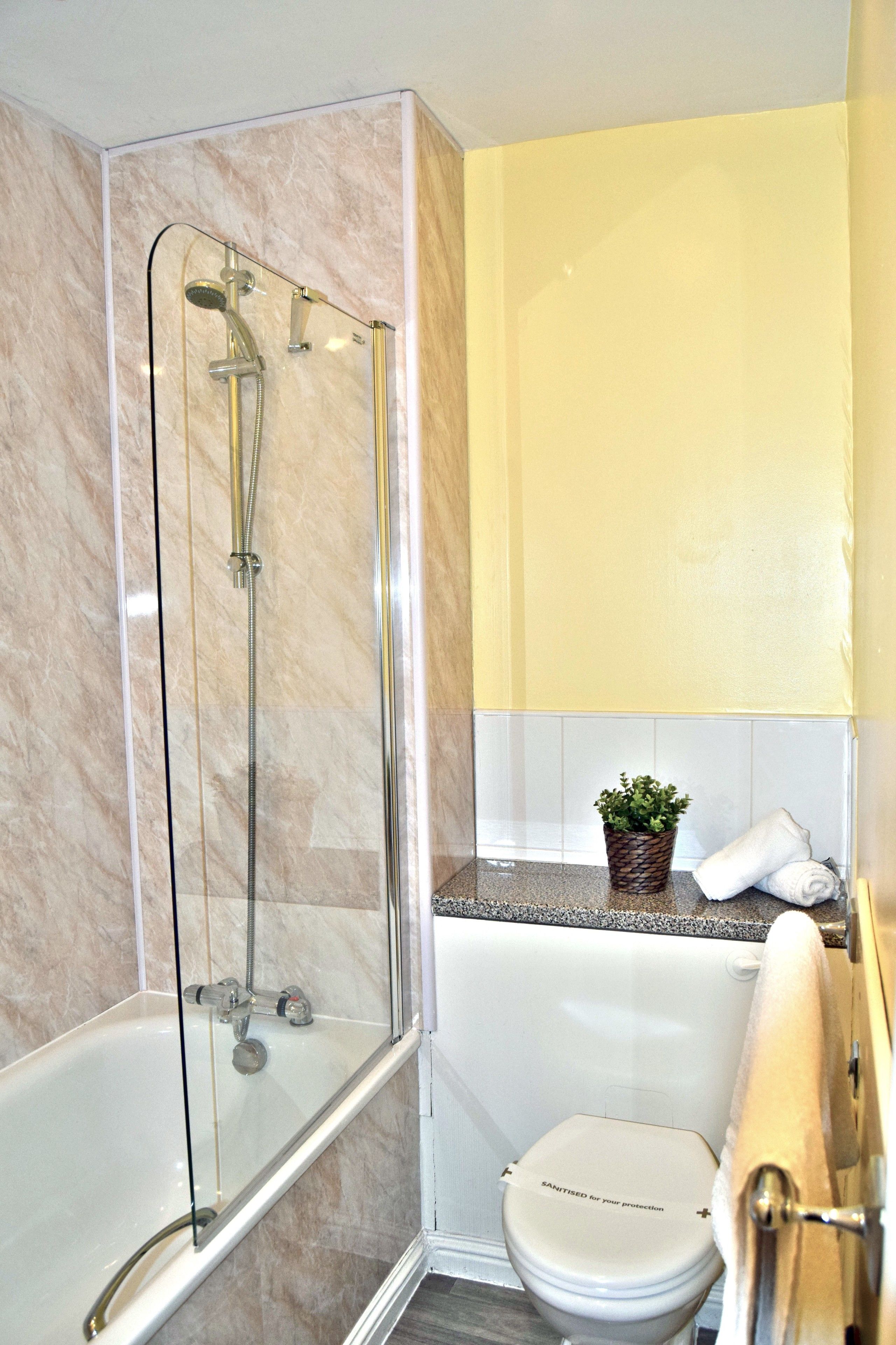 Ein Badezimmer mit einer gläsernen Duschkabine, einer weißen Badewanne und einer Toilette.