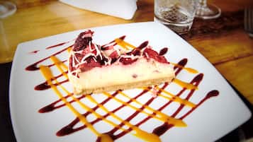 A slice of cheesecake with fruit and sauce on a white plate.