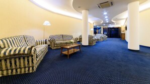 A hotel lobby with striped sofas, a coffee table, and a blue carpet. - Hotel Hermitage (Polla)
