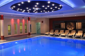 Una piscina con sillas de descanso, un techo con luces que simulan estrellas y una pared con un gran caracter chino.
