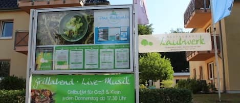 Segnaletica di un ristorante con posti a sedere all'aperto e musica dal vivo.