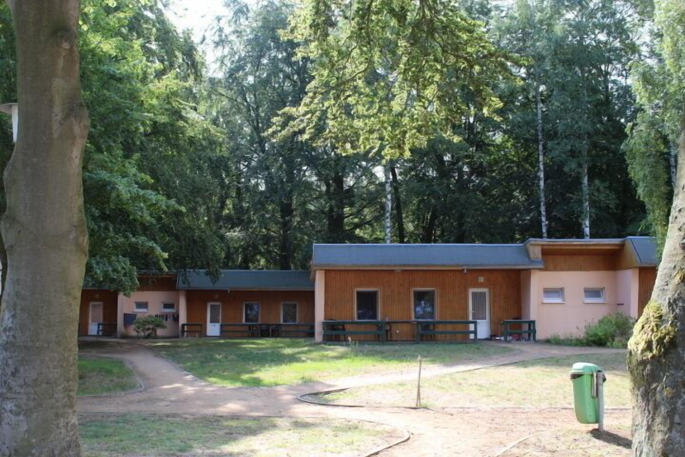 Un chalet comprenant plusieurs cabanes en bois, un bâtiment principal et un chemin de terre menant aux cabanes.