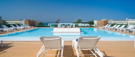 Zona junto a la piscina con sillones de descanso y vista al océano.
