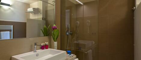 A modern bathroom with a glass-enclosed shower, a white sink, and a mirror above it.