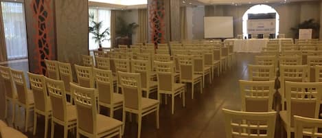 A conference room with rows of chairs facing a whiteboard and a projection screen.