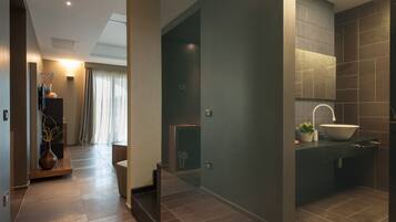 Un baño moderno con un espejo grande, un lavabo sobre encimera y una pared con azulejos oscuros.